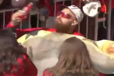 Travis Kelce chugs beer while holding cutout of shirtless Jason at Chiefs Super Bowl parade